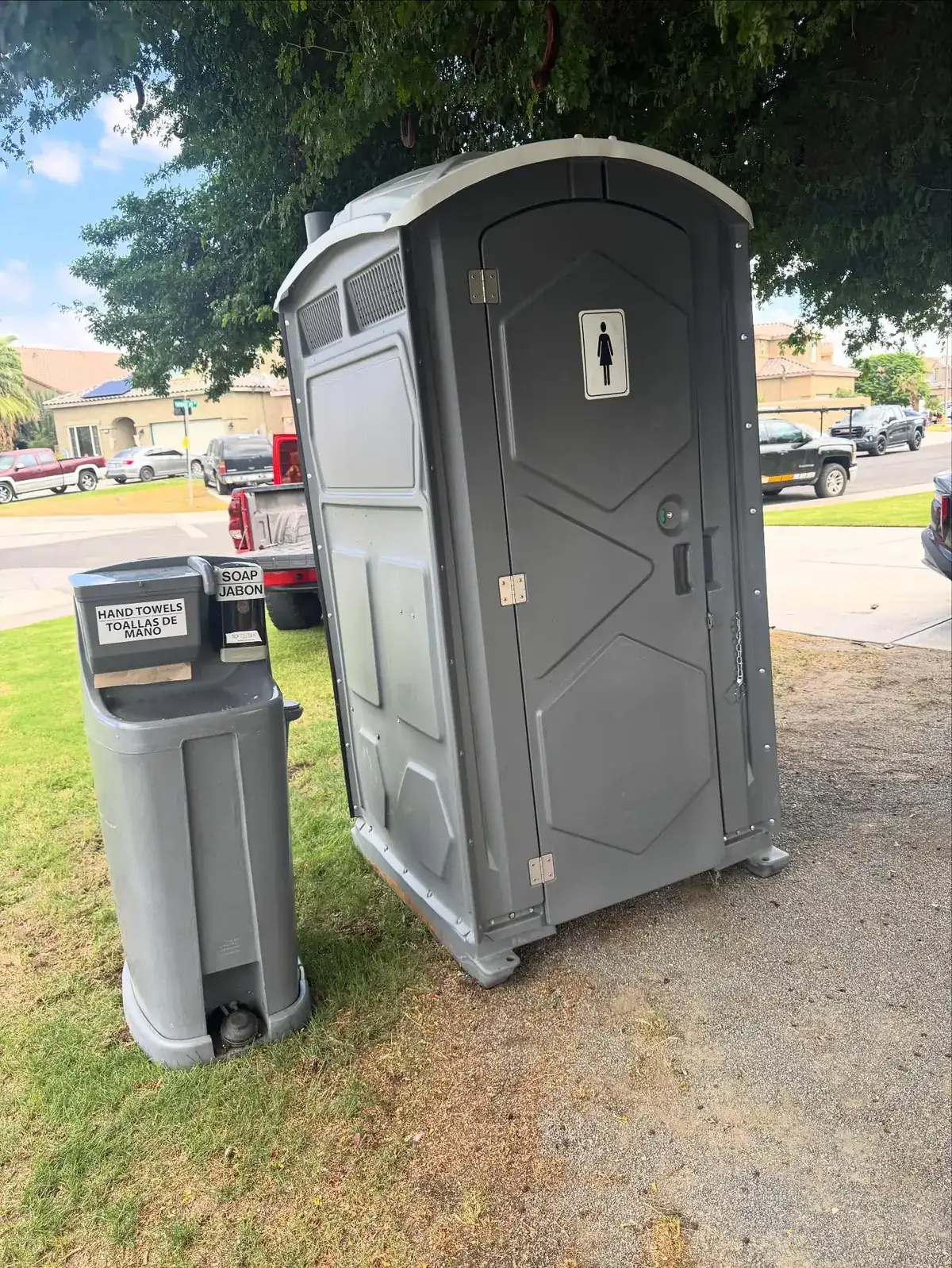 A standard unit and a hand wash station set on level grass beside a home